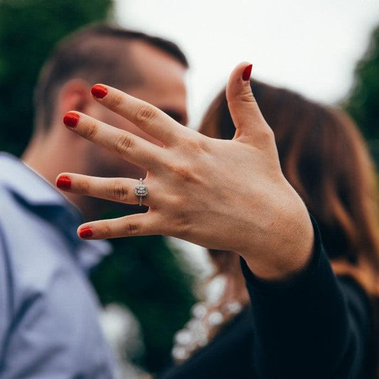 Two people kissing, hand raised to show a new engagement ring