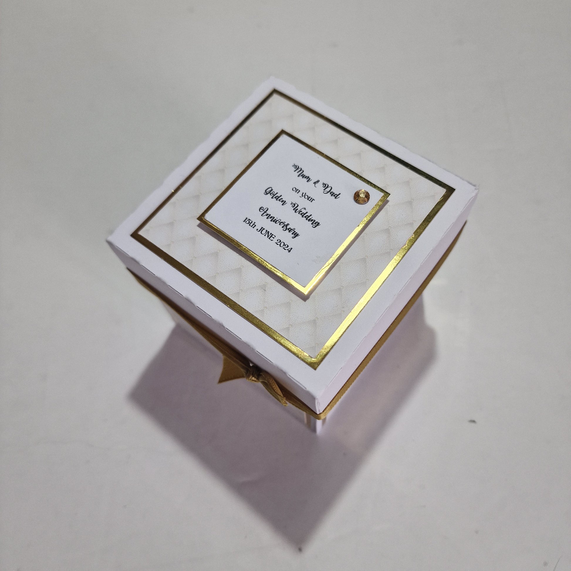 Golden Wedding Anniversary Exploding Box featuring a white box with gold trim and ribbon, designed as a keepsake for 50th anniversaries, offering customizable messages and photo slots for personalization.