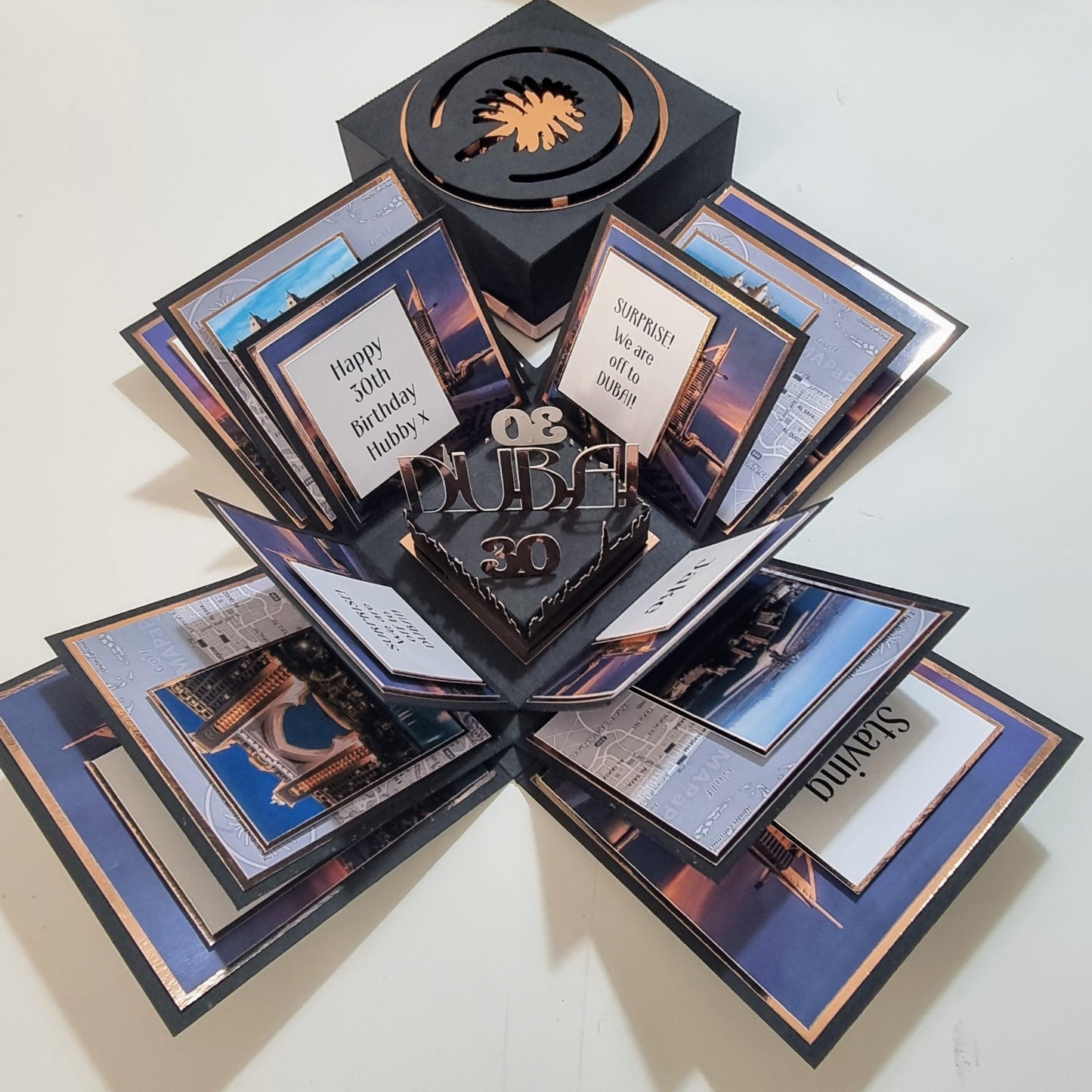 Exploding Occasions Box - Trip Reveal Dubai, featuring a freestanding Dubai icon, architectural panels, and personalized elements inside a black box, perfect for a surprise trip announcement.