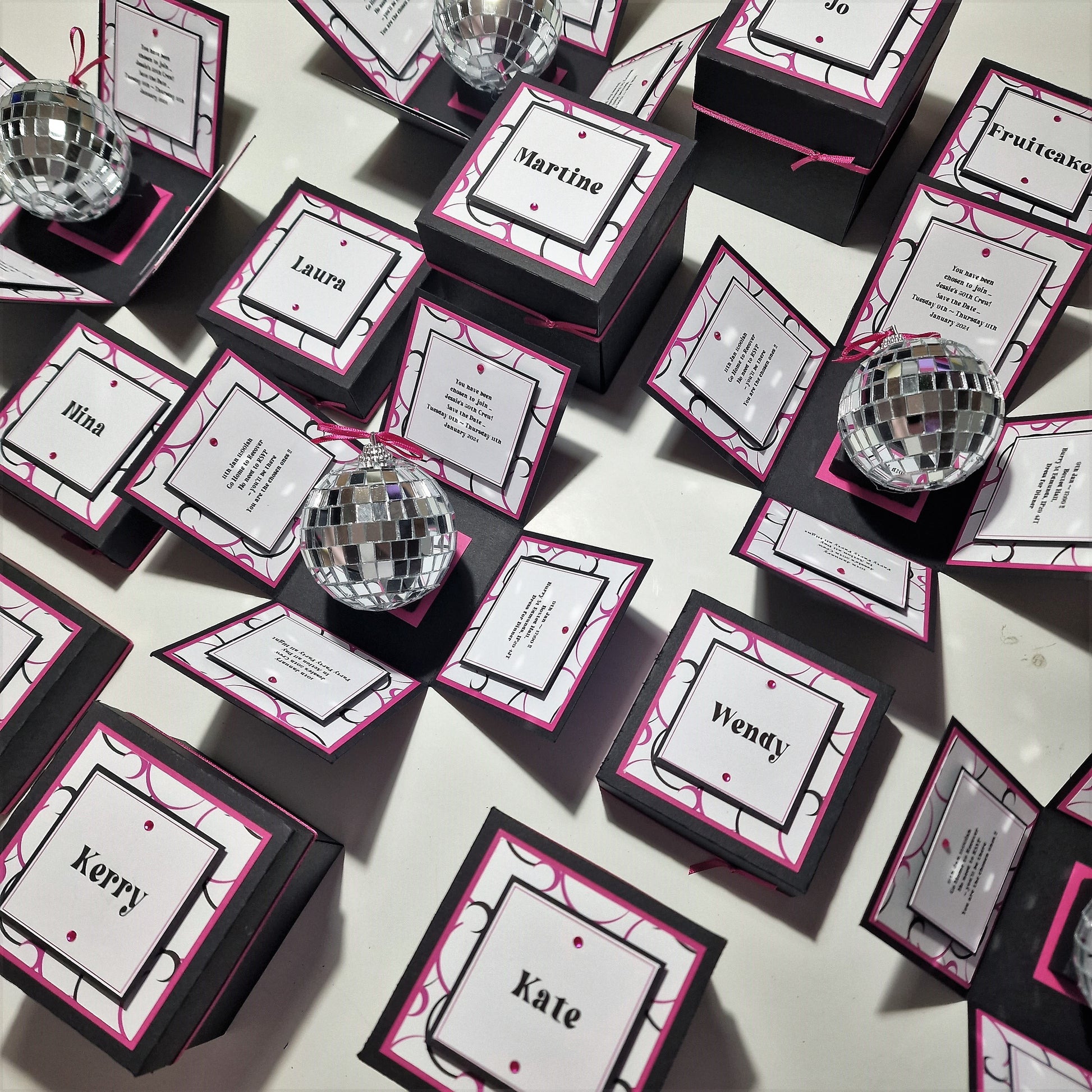 Box'd Disco Themed Invitation Boxes featuring black and pink designs, adorned with mirror balls and personalized cards, offering customizable elements for unique wedding invitations.