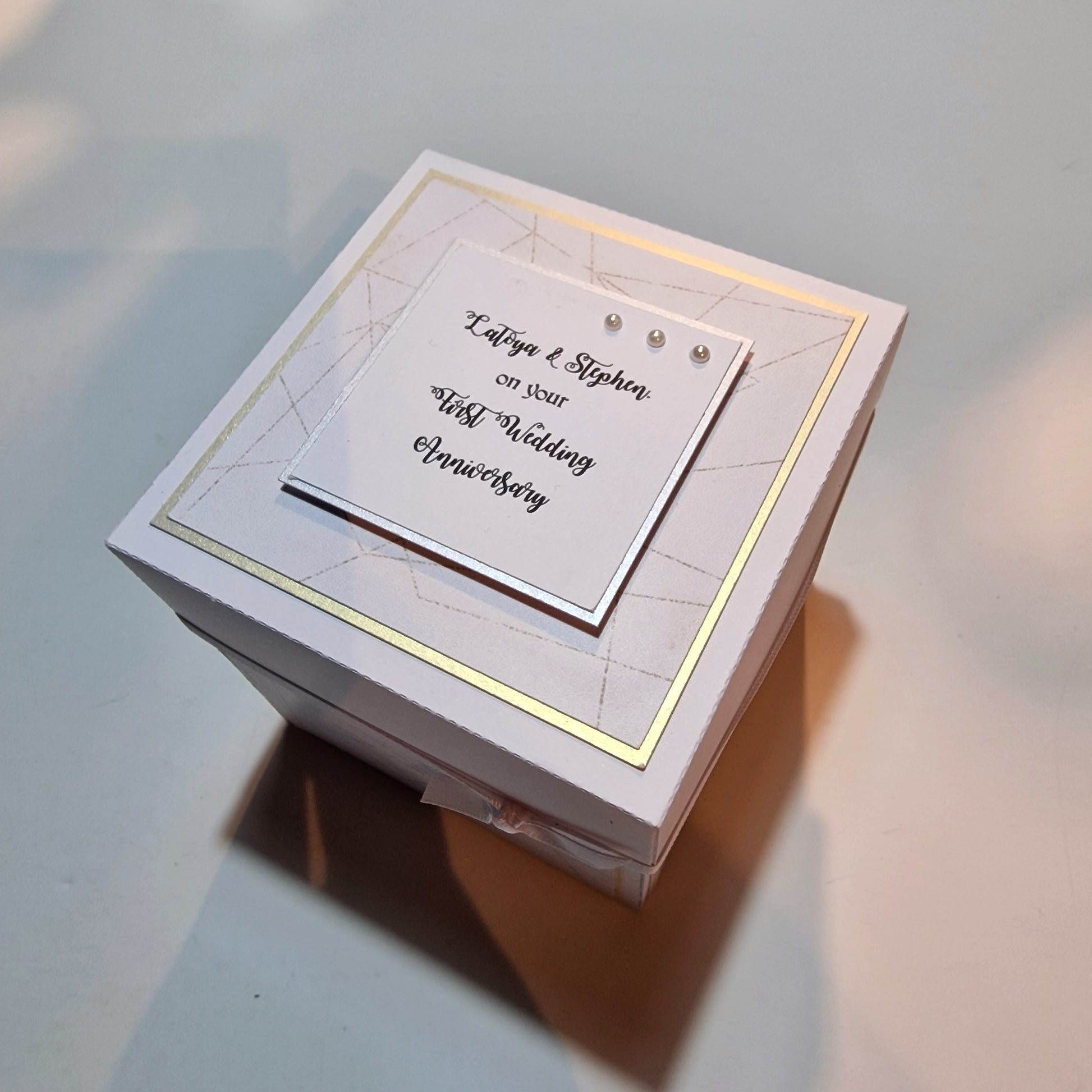 First Wedding Anniversary Exploding Box shown with a white box and a card featuring black text and three pearls, highlighting its elegant and customizable design for a memorable keepsake.