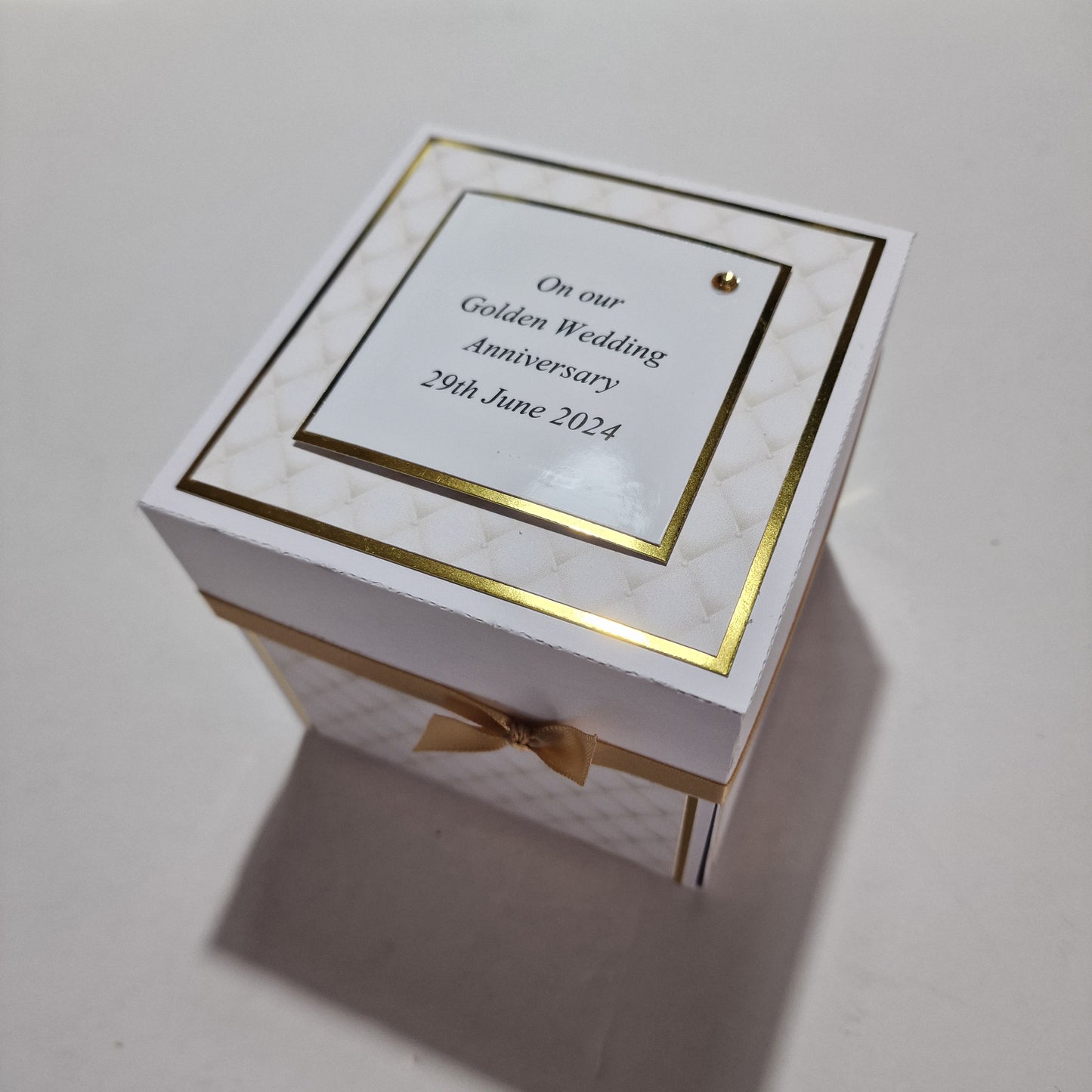 GOLDEN Wedding Anniversary Exploding Box with white base, gold trim, and ribbon. Features customizable panels inside for names, dates, messages, and photos, celebrating love and commitment.