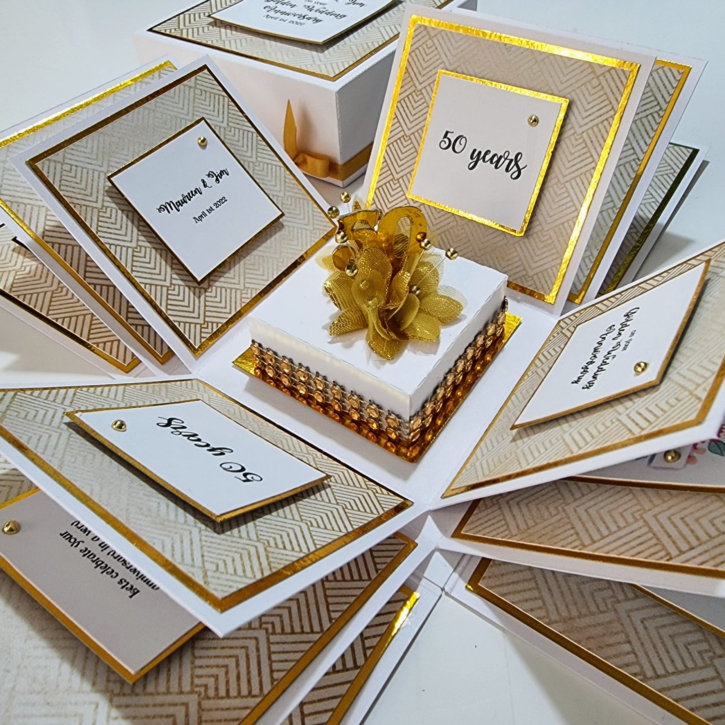 Golden Wedding Anniversary Exploding Box, elegantly decorated with a gold bow and ribbon. Features a white base with golden accents and includes customizable messages and photos for a cherished keepsake.