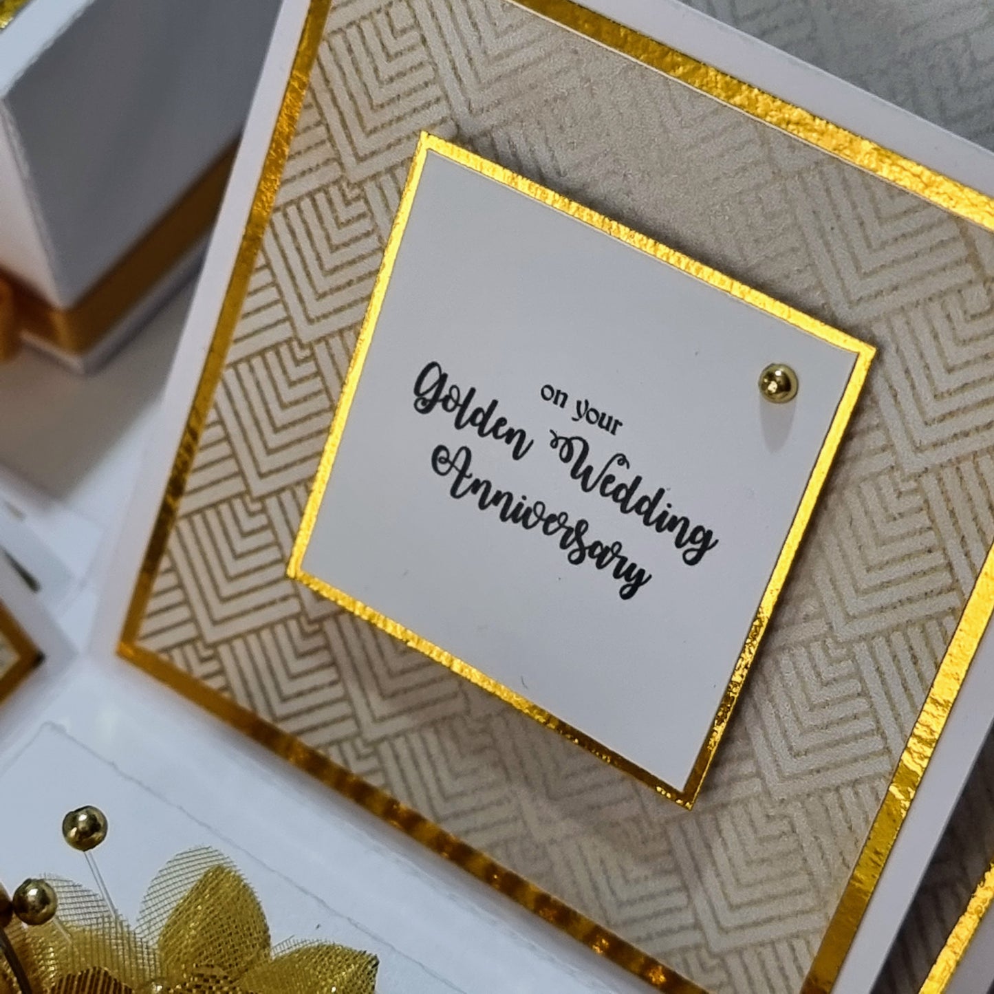 Golden Wedding Anniversary Exploding Box: A close-up of a white box with gold trim, featuring intricate gold details and customizable panels for a 50th anniversary keepsake.