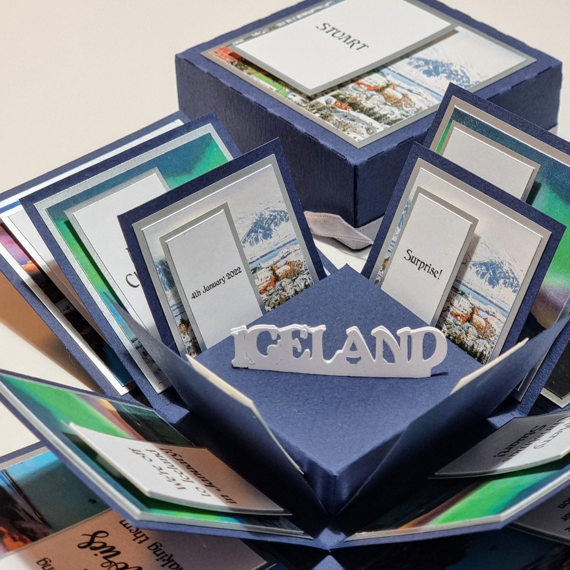 Exploding Occasions Box - Trip Reveal ICELAND, featuring an intricately designed blue box with Iceland-themed elements, cards inside, and a freestanding centerpiece. Perfect for surprise trip announcements.