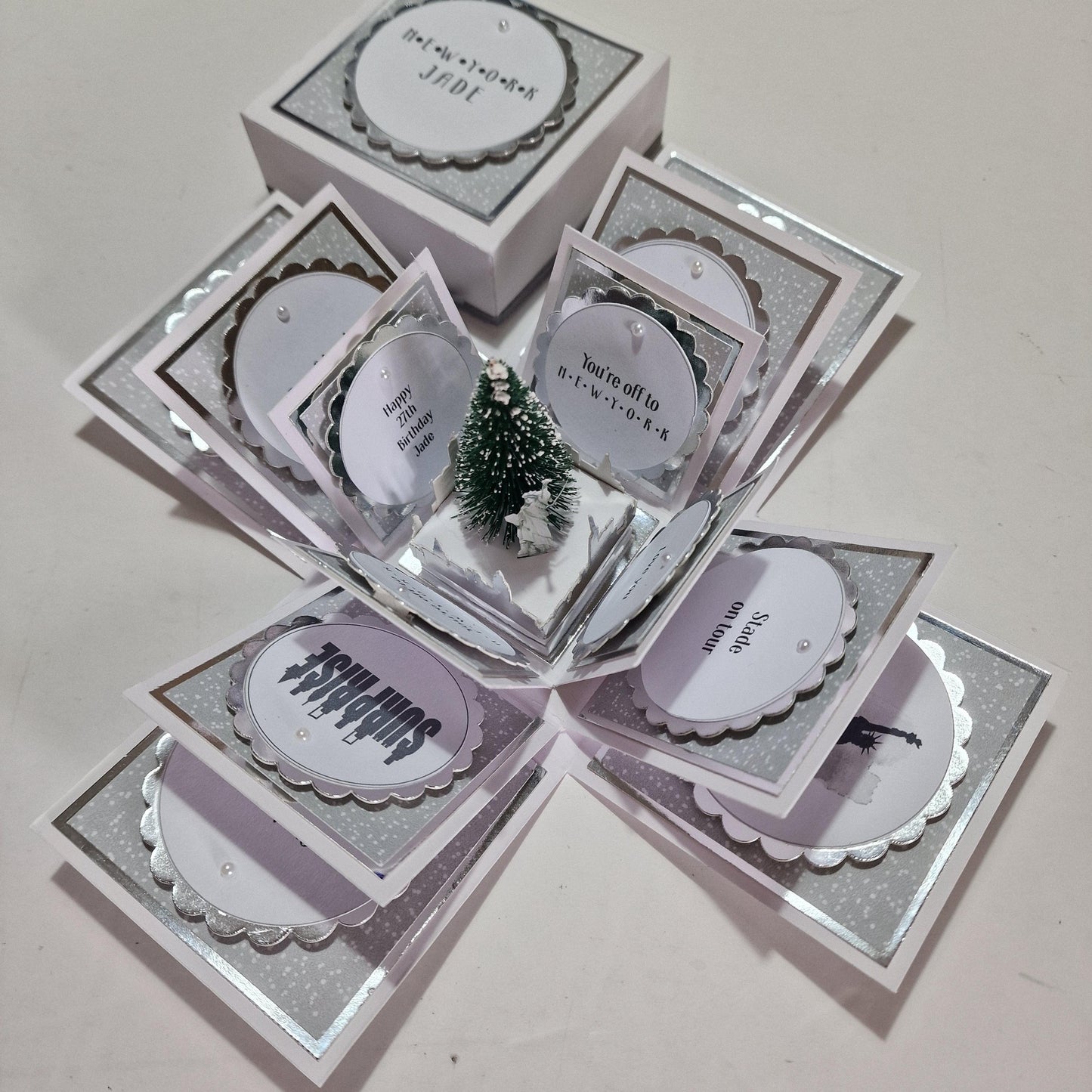 New York Christmas Trip Reveal Box featuring a small snow-dusted Christmas tree inside, adorned with a label and intricate details, perfect for personalizing your holiday surprise.