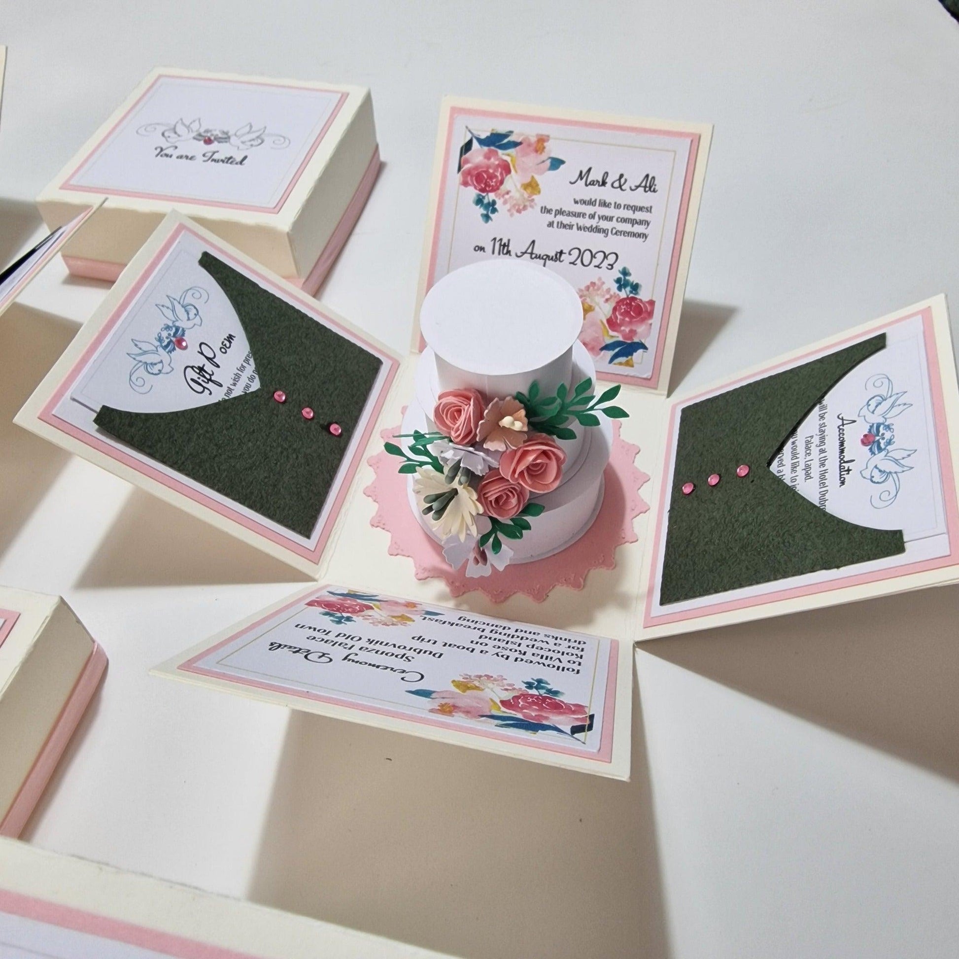 Bohemian Bespoke Exploding Wedding Invitations featuring a three-tier circular wedding cake with floral decor inside a pastel box, including invitation and venue panels, menu cards, and RSVP card.