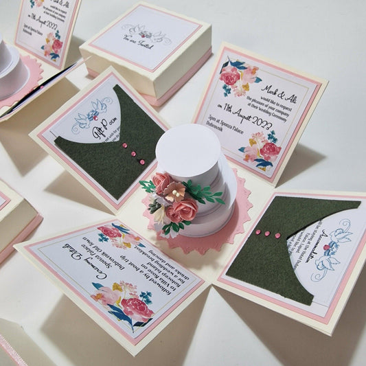 Bohemian Bespoke Exploding Wedding Invitations featuring a central three-tier cake adorned with flowers, set within a pastel-colored box with fixed invitation and venue details panels.