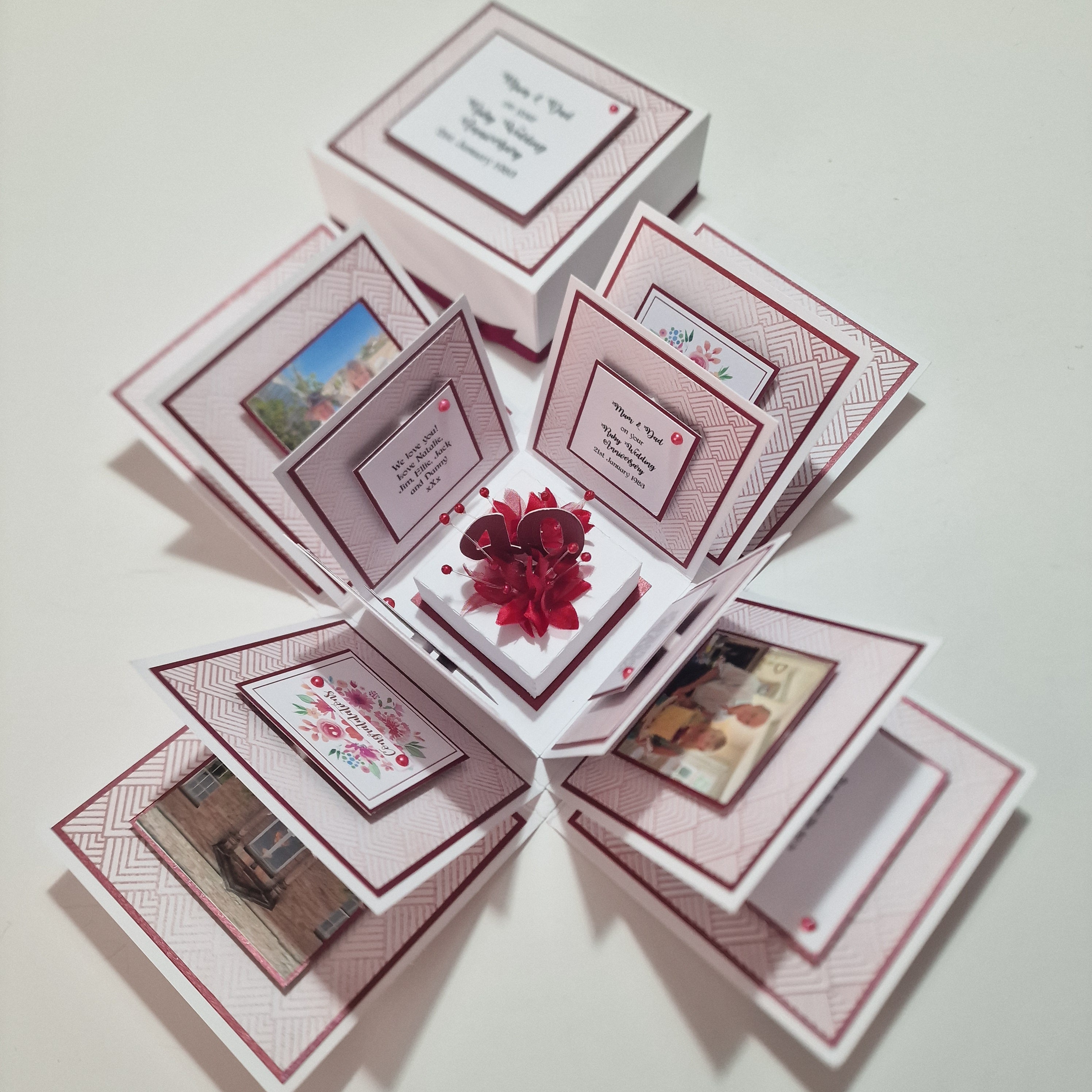 Ruby Wedding Anniversary Exploding Box featuring white base with ruby-red accents, adorned with cards and photos of a couple, celebrating 40 years of love and commitment.