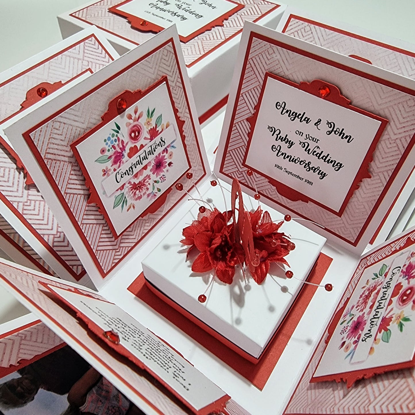 Ruby Wedding Anniversary Exploding Box featuring elegant white panels with red floral accents, showcasing customizable messages and photos, offering a personalized touch for celebrating love and commitment.