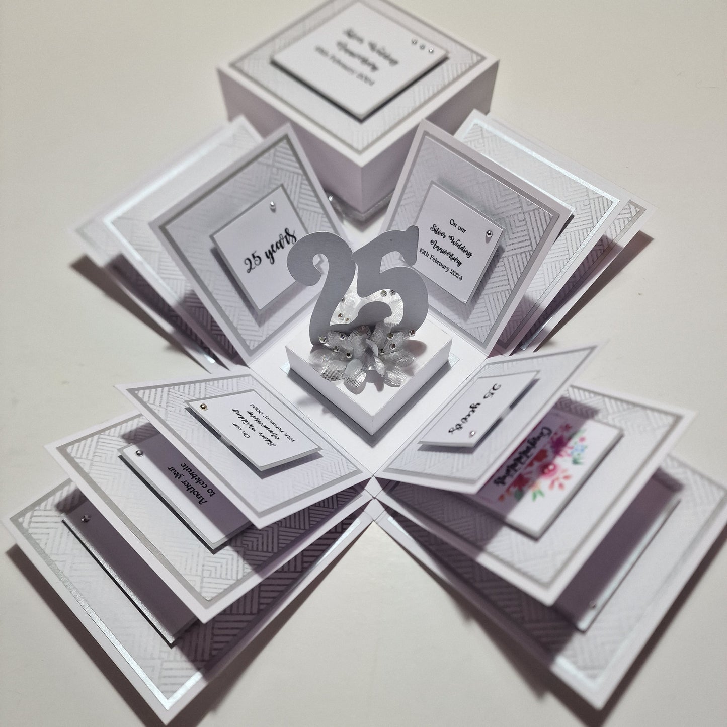 Silver Wedding Anniversary Box featuring a white paper design with numbers and text, elegantly adorned with silver accents. Perfect for personalizing with names, dates, and heartfelt messages for a memorable keepsake.