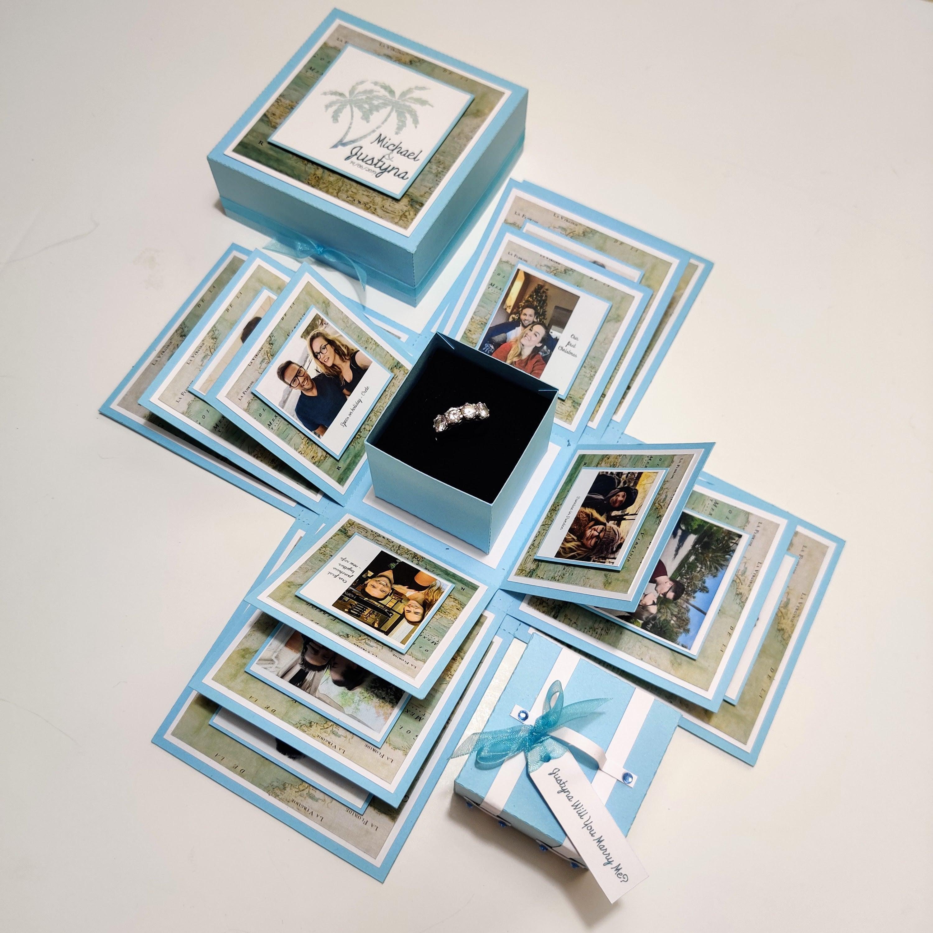 Travel Themed Proposal Box featuring a pastel blue design with map papers and Polaroid-style photos, perfect for an unforgettable Will You Marry Me engagement ring presentation.