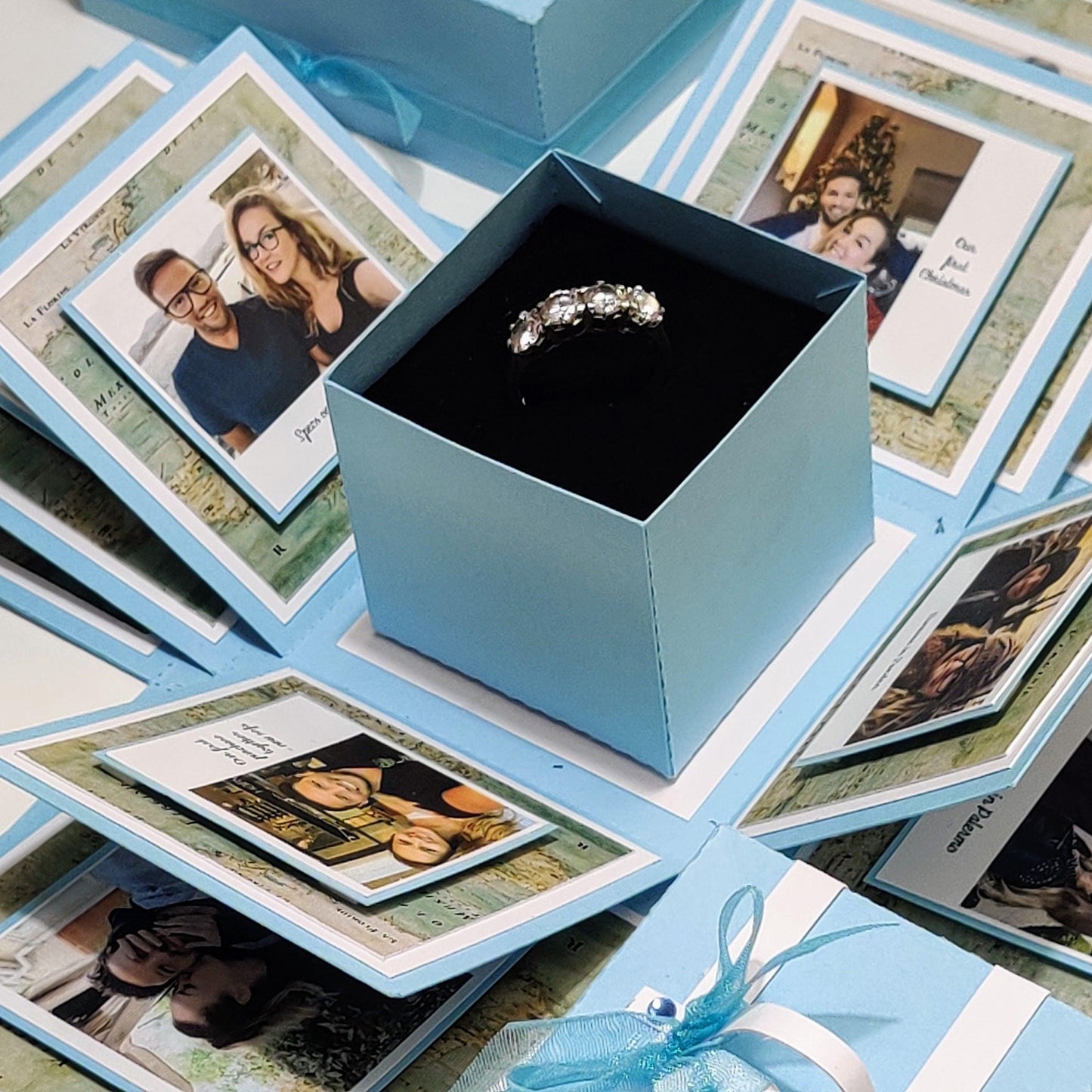 Travel Themed Proposal Box featuring a blue box with an engagement ring inside, designed for memorable proposals with customizable photo and message options, part of the Exploding Proposal Ring Box collection.