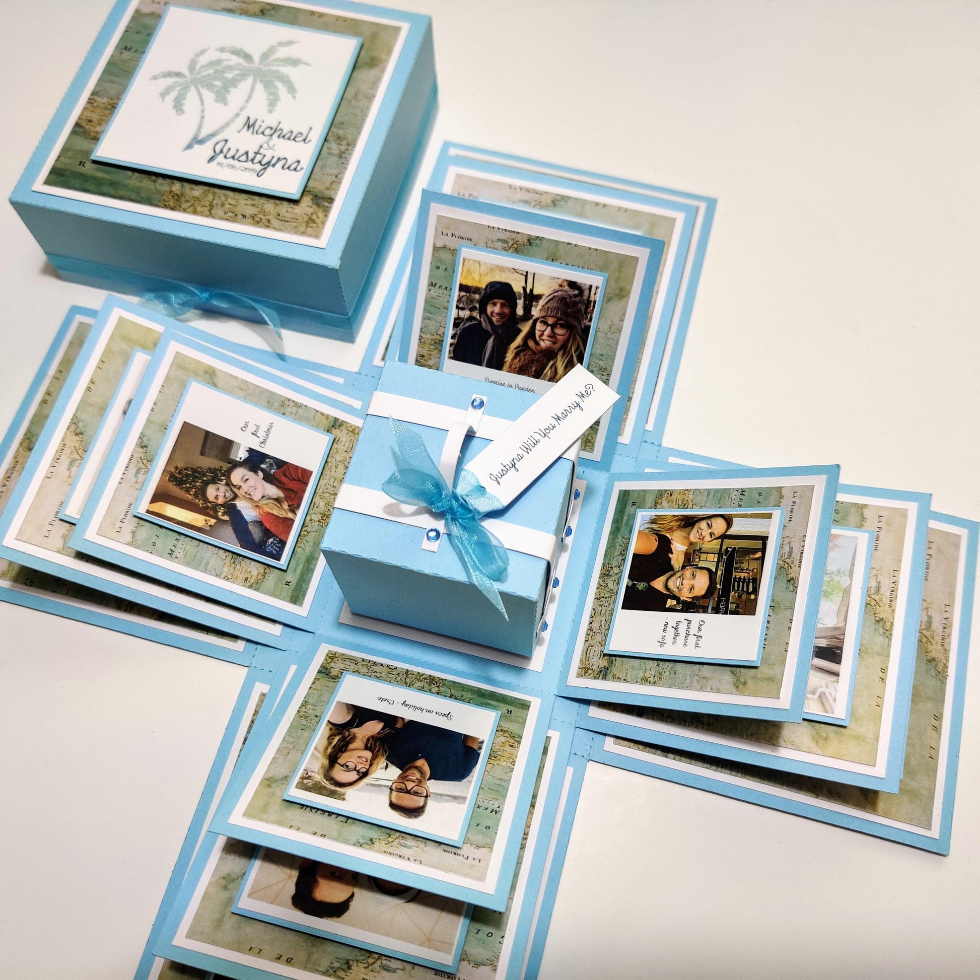 Travel Themed Proposal Box featuring a blue box with map papers, Polaroid-style photos, and a ribbon, ideal for an unforgettable Will You Marry Me? engagement moment.