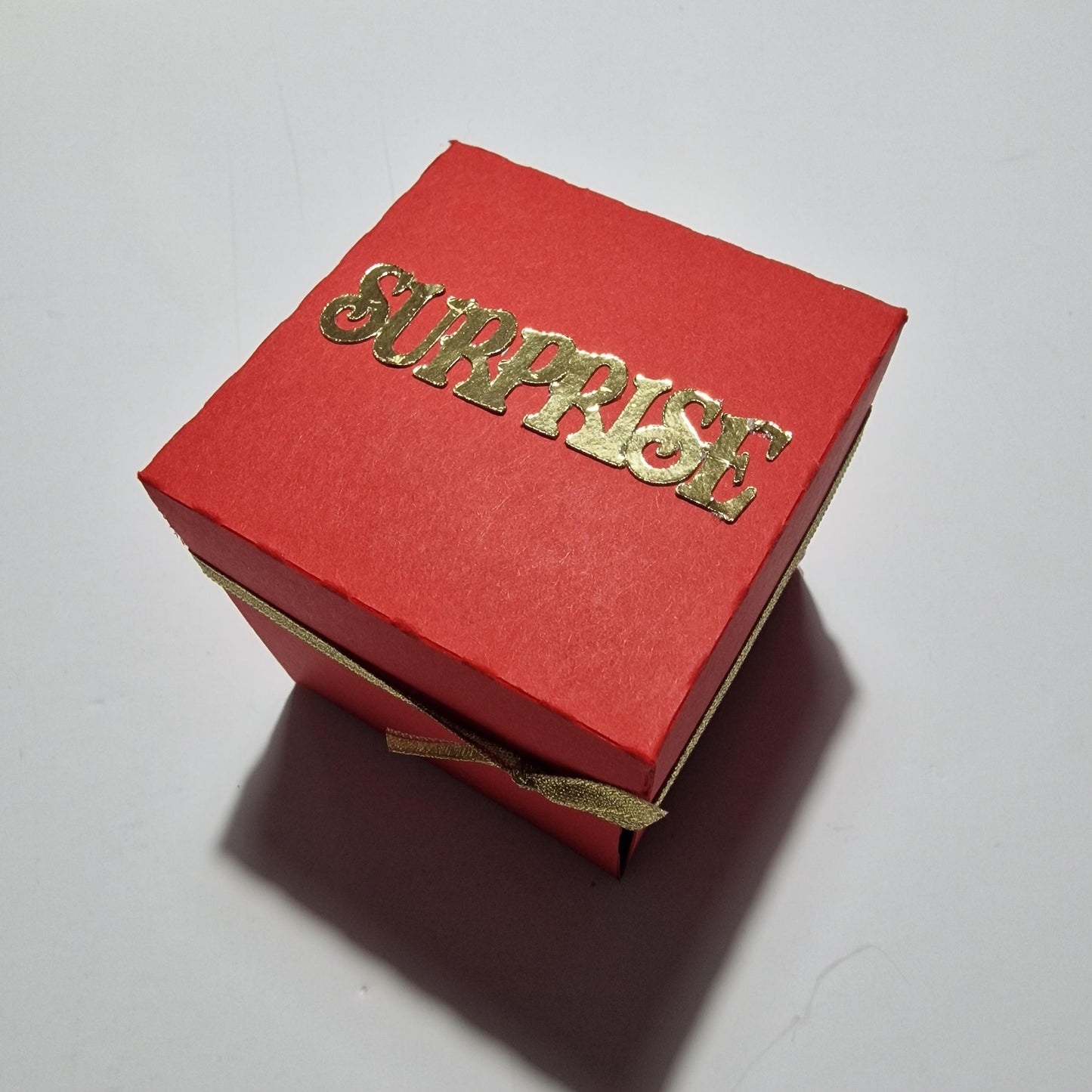 Exploding Occasions Box - Trip Reveal VENICE: A red box with gold text and ribbon, featuring Venice-themed details and a freestanding gondola, designed for special surprise trip celebrations.