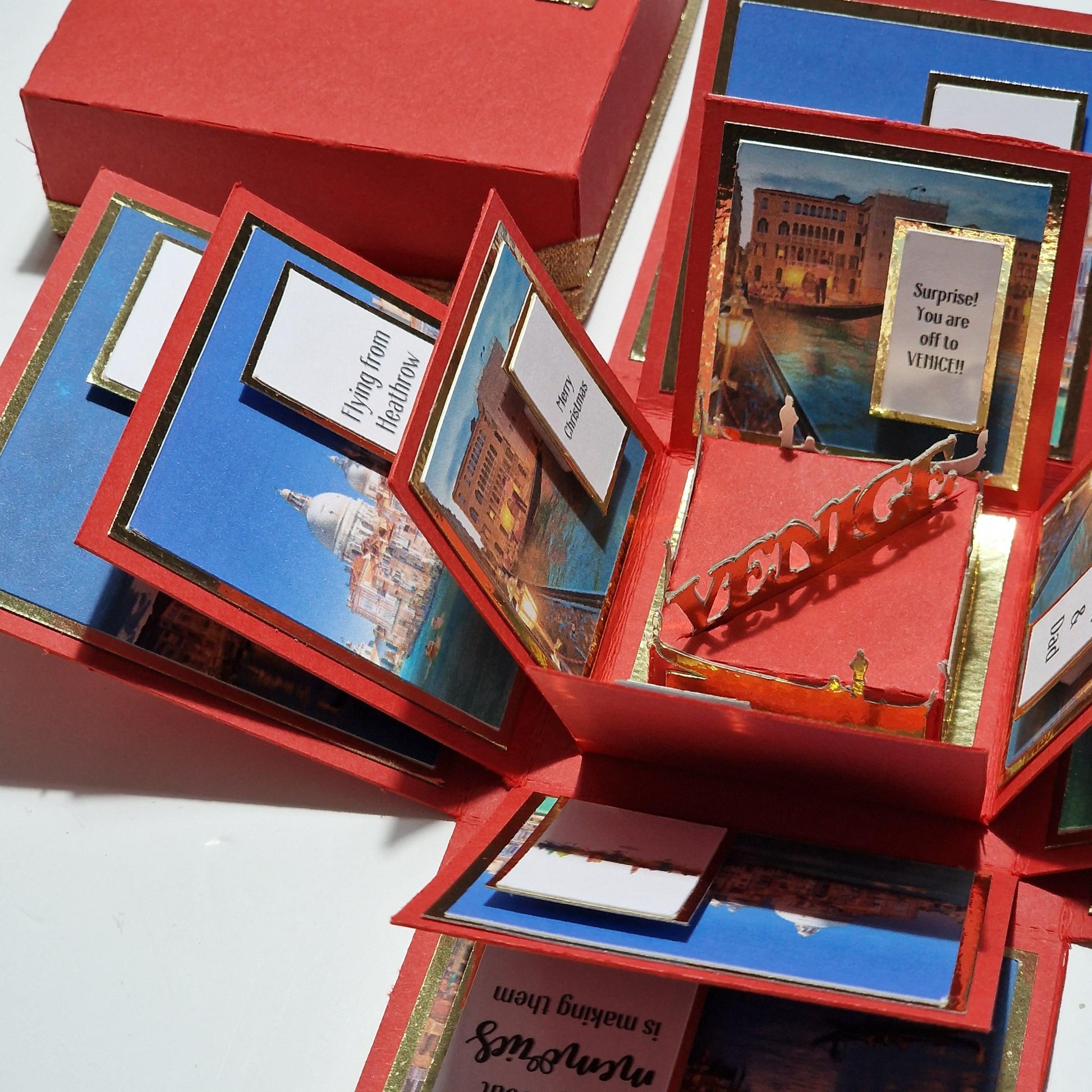 Exploding Occasions Box - Trip Reveal VENICE, showcasing a red box adorned with Venice-themed images, freestanding gondola, and architectural panels for a personalized surprise trip reveal experience.