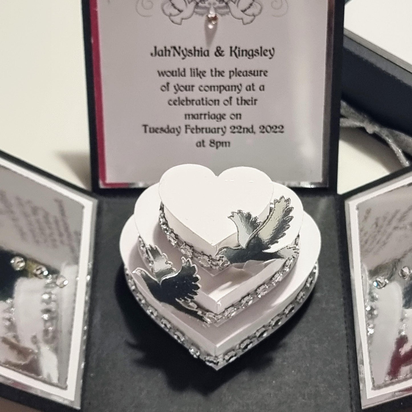 Black & Silver Exploding Wedding Invitation Box featuring a heart-shaped design with doves on a tiered wedding cake, complete with invitation and venue details, menu cards, and RSVP.