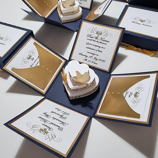 Navy Blue & Gold Exploding Wedding Invitation Box featuring a heart-shaped cake with doves, invitation details, and pull-out menu cards, showcasing luxurious bespoke wedding stationery.