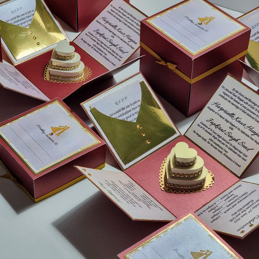 Custom Designed & Built Exploding Wedding Invitation Boxes featuring intricate red and gold designs with heart-shaped elements and a gold-trimmed box, showcasing luxurious, bespoke wedding stationery.